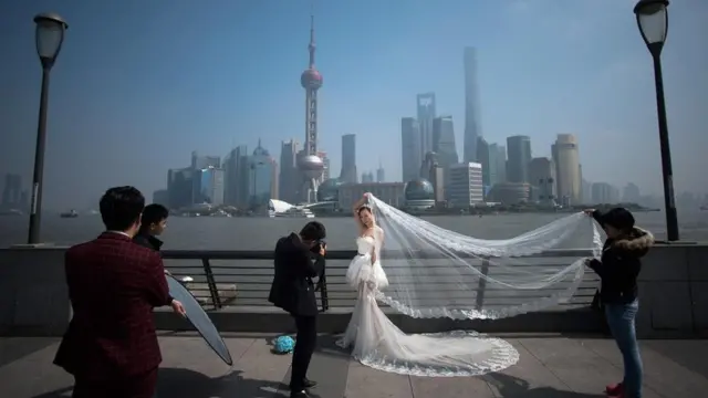 عروس تقف فوق جسر ليلتقط لها البعض صور الزفاف