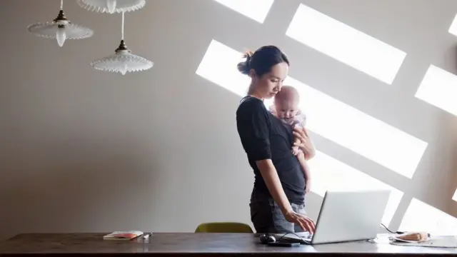 Mulher trabalhando com bebê no colo