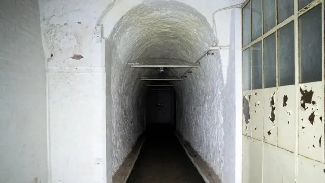 从区域政府办公室出发，有一条隧道通向一堵砖墙。墙后面的工厂空无一物（图片来源： William Park）