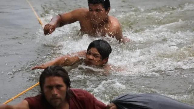 Migrantes caminan por el río para cruzar a México.