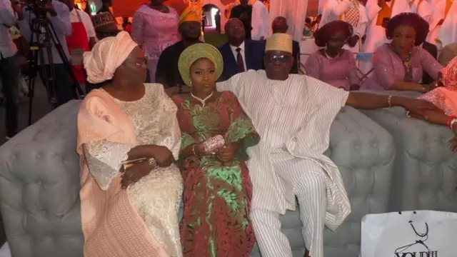 Iyawo ọsingin joko si aarin iya ati baba rẹ