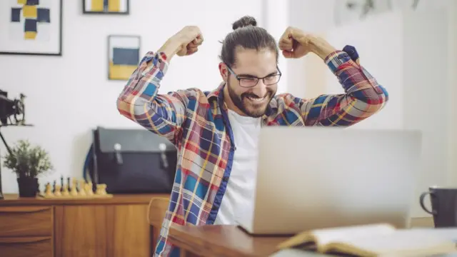 Homem comemorando diante do computador