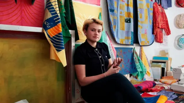 Poppy Nash sitting amongst her material designs