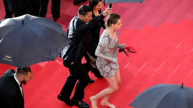 Kristen Stewart Kann festivalının qırmızı xalısından ayaqyalın keçir - ya təşkilatçıların qadınlardan məşhur dress-kod tələbinə görə, ya da yağış yeri sürüşkən etdiyi üçün.
