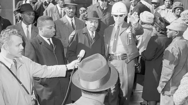 ডালাস কাউন্টরি শেরিফের অফিসের সামনে মার্টিন লুথার কিং। শত শত মানুষ লাইনে দাঁড়িয়েছেন ভোটার হওয়ার জন্য।