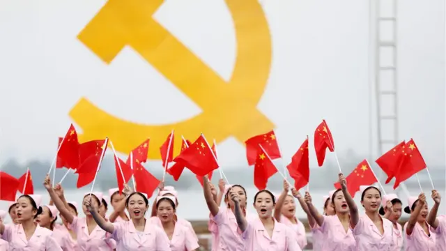 Mujeres chinas frente a un símbolo comunista