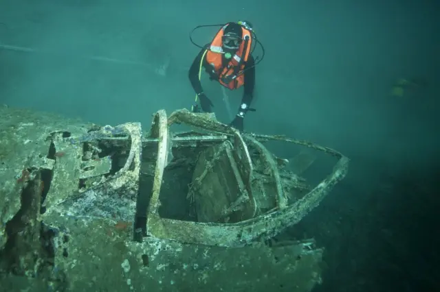 A French military diver member of the FS Pluton M622 navy de-mining ship, swims above the wreck of an USAAF P-47 Thunderbolt (Warthog) US fighter plane