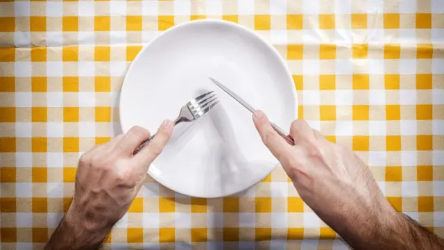 Tenedor y cuchillo a punto de raspar un plato.