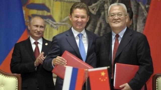 Gazprom CEO Alexei Miller (centre) and CNPC Chairman Zhou Jiping shake hands as Russian President Putin looks on during the signing ceremony in Shanghai