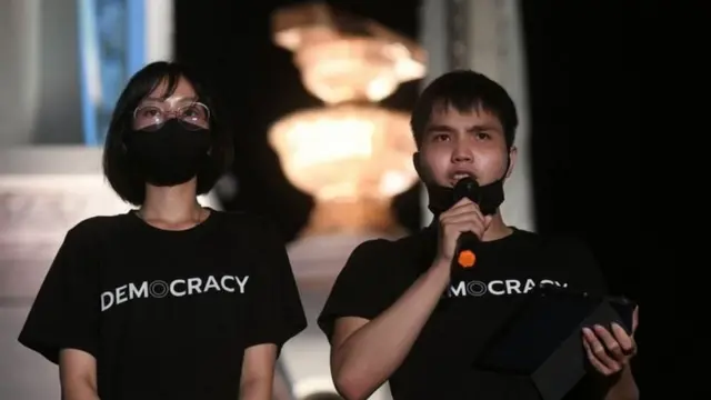 ทัตเทพถือไมโครโฟนบนเวทีชุมนุม