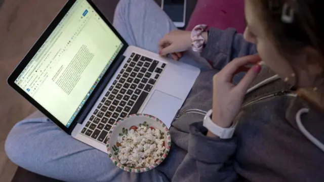 Louisa, 13, comendo pipocas enquanto faz liçãosport galerabetcasa