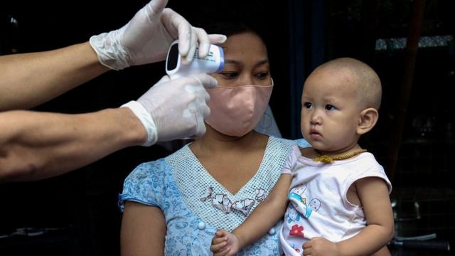缅甸仰光医疗人员挨家挨户排查新冠肺炎患者时给一名小孩量体温（17/5/2020）