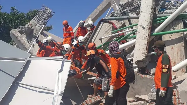 Indonesia"s National Search and Rescue Agency shows rescuers retrieving a body from the rubble of a building in Palu, Indonesia"s Central Sulawesi, following the September 28 earthquake and tsunami.