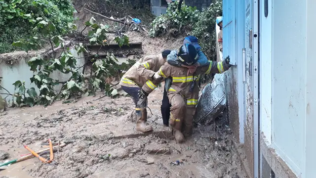 부산의 한 주택 인근에 토사가 떠밀려와 고립된 주민을 소방대원들이 구조하고 있다