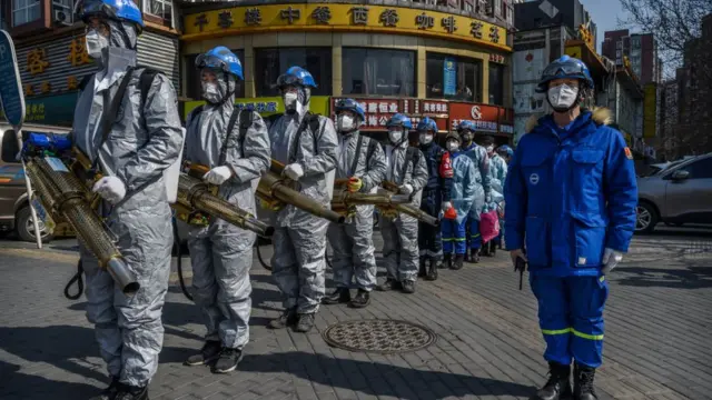 На фото - отряд дезинфекторов в марте в Ухане