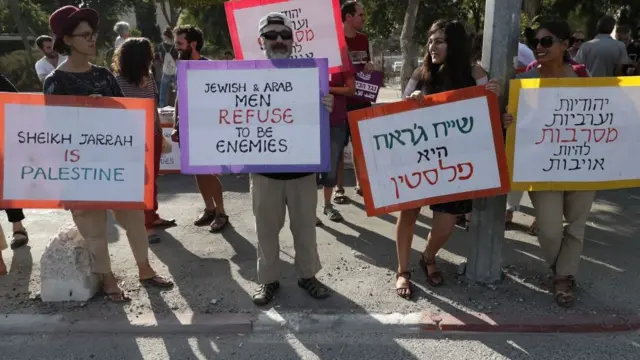 শেখ জারাহ এলাকায় ইহুদিদের দখল করা একটি বাড়ির সামনে প্রতিবাদ করছেন ফিলিস্তিনি এবং ইসরায়েলি শান্তি আন্দোলনকারীরা।