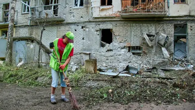 युक्रेनको खार्किभमा रुसी आक्रमणपछि सफाइ गर्दै एक महिला
