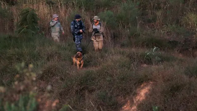 Policiais com cachorro farejador durante buscas a Lázaro