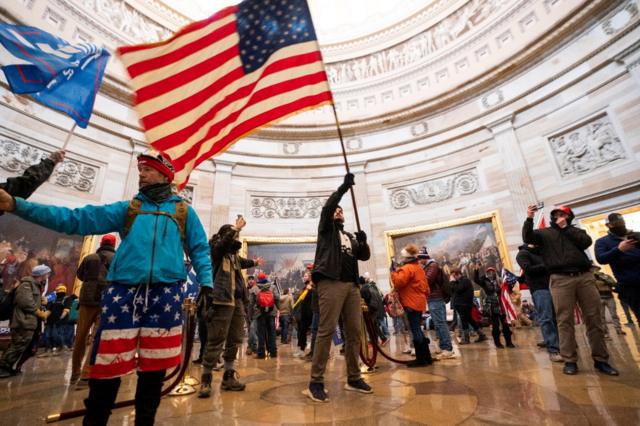 抗议人群冲进国会大厦，挥舞美国国旗