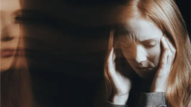 Mujer sosteniéndose la cabeza.