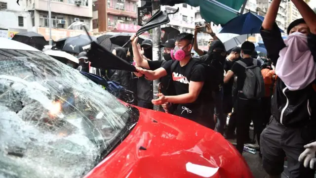 Người biểu tình tấn công chiếc xe taxi đâm vào đoàn người biểu tình làm bị thương cả hai chân của một cô gái hôm 6/10.