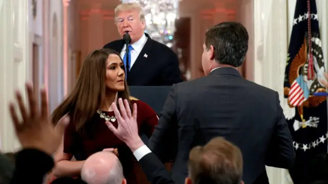 A White House staff member steps in to try to take the microphone away from CNN's Jim Acosta as he questions President Trump