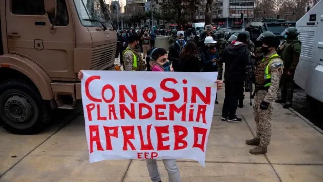 Manifestante de máscara segura cartaz que diz: 'Com ou sem pandemia, aprovo!'