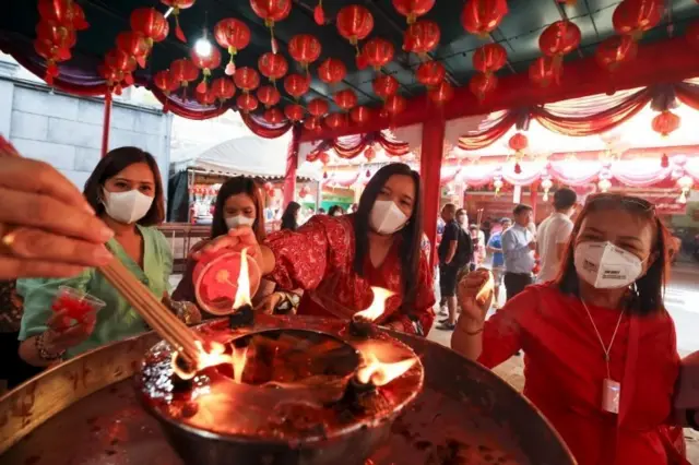 People wear protective masks as they pray at a Chinese temple in Chinatown in Bangkok, Thailand, 28 January 2020.