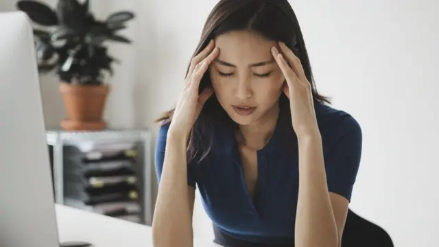 A young female office worker appears stressed