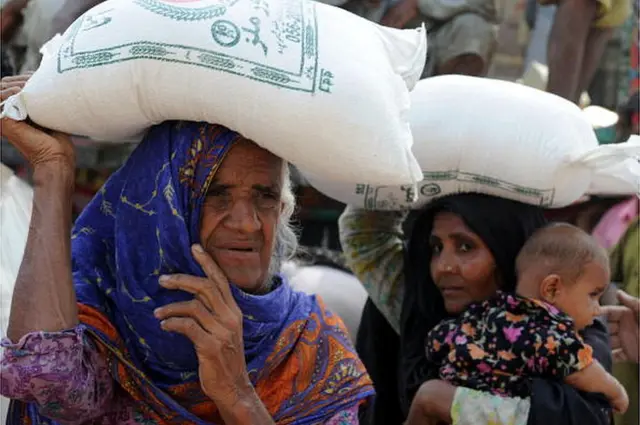 దాతల సహాయాన్ని మోసుకెళ్తున్న మహిళలు