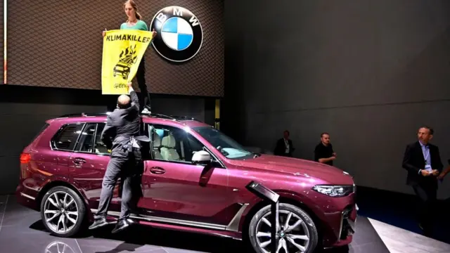 فعالان گروه صلح سبز با ایستادن روی ماشین‌های نمایشگاه اعتراض خود را نشان دادند