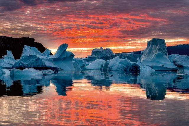 A sunrise over a number of icebergs