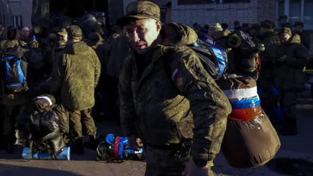 Мужчина с вещмешком на фоне армейского грузовика