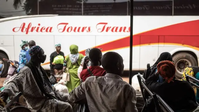 Des voyageurs sont assis sur des bancs dans une gare routière en attendant la reprise du transport transfrontalier à Bamako, le 11 janvier 2022.