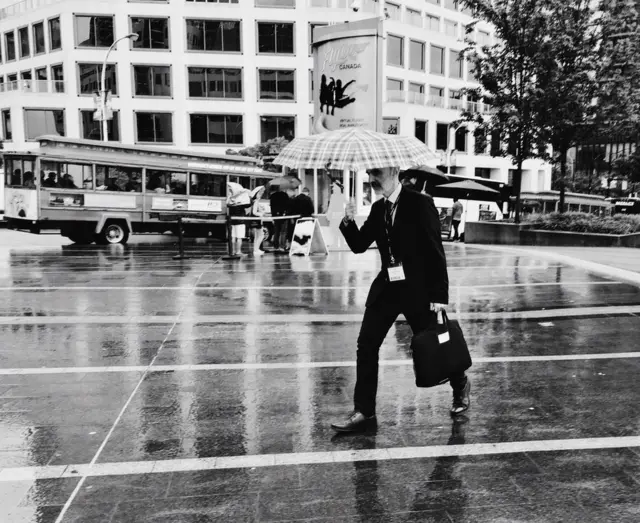 Hombre cruzando una calle bajo la lluvia