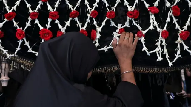 انڈیا کے شہر کلکتہ میں ایک خاتون امام حسین کے تابوت کی شبیہہ کے ساتھ کھڑی ہیں