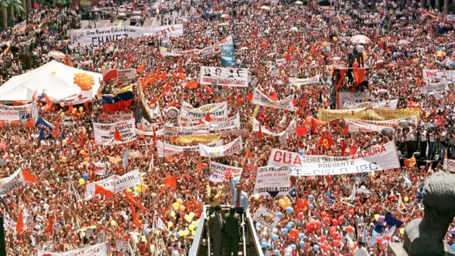 Multidão reunida com cartazes para ouvir Chávez falar