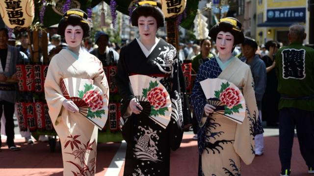 Women in kimono pose for a photograph in the street of Asakusa during Sanja festival on May 19, 2019