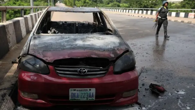 A policeman walks past a car burnt by supporters of an imprisoned leader of the Islamic Movement of Nigeria (IMN) Ibrahim Zakzaky around the national assembly building in Nigeria's capital Abuja, on July 9, 2019.