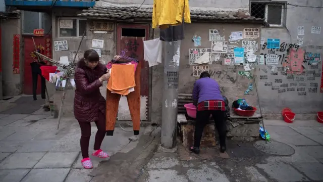 북경의 이민자 마을에서 여성들이 옷을 세탁하고 말리고 있다