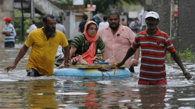 ගංවතුරට කොටු වූ නිවසින් පිටව යාමට කානතාවකට ආධාර කරන පිරිසක්