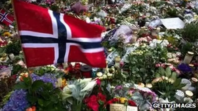 A Norwegian flag blows in the wind surrounded by flowers and candles outside the Oslo cathedral on July 26, 2011