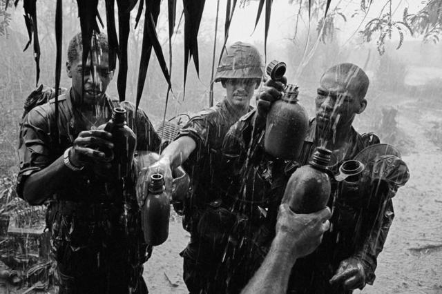 Soldiers capture rainwater in their flasks