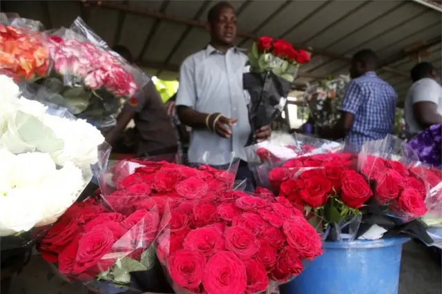 A man sells roses of various colours from an outdoor stall in Abidjan, Ivory Coast - Friday 12 February 2021