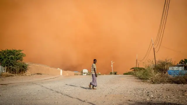 Un homme marche devant une tempête de sable à Dollow, dans le sud-ouest de la Somalie. Des personnes de tout le Gedo en Somalie ont été déplacées en raison de la sécheresse et ont été forcées de venir à Dollow, dans le sud-ouest, pour chercher de l'aide