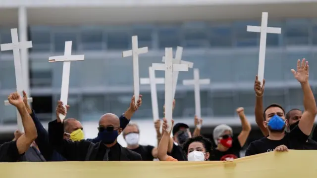 Pessoas com máscara levantando cruzescodigo promocional betanoprotesto