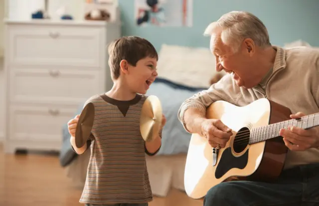 Un homme age et un petit garcon font de la musique