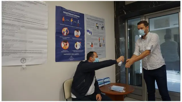 A poll worker offers hand sanitiser at a voting booth during the June parliamentary election in Serbia