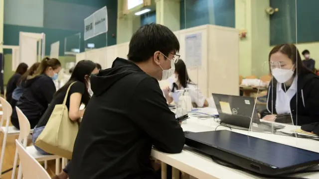 香港某社区疫苗接种中心内工作人员为已预约接种市民核对资料（中新社图片13/3/2021）