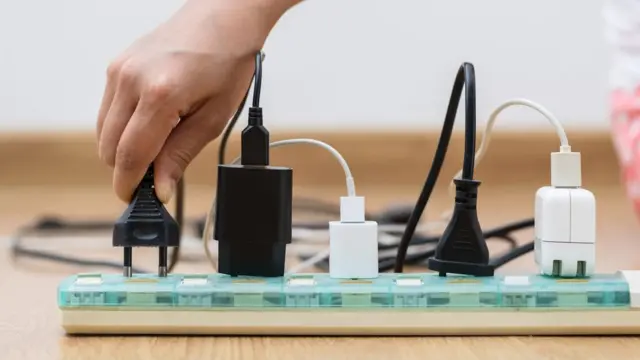 Una persona enchufado aparatos a una extensión